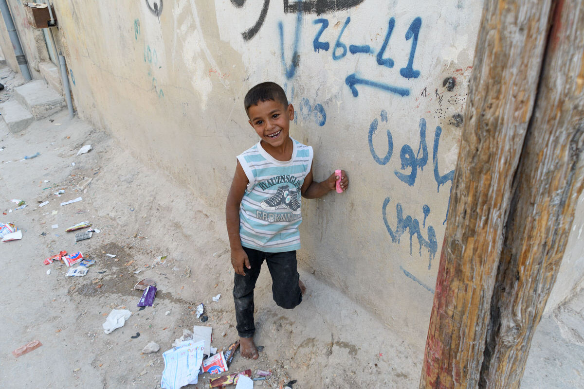 A happy child holding his new stick of sidewalk chalk in Jerash refugee camp.
