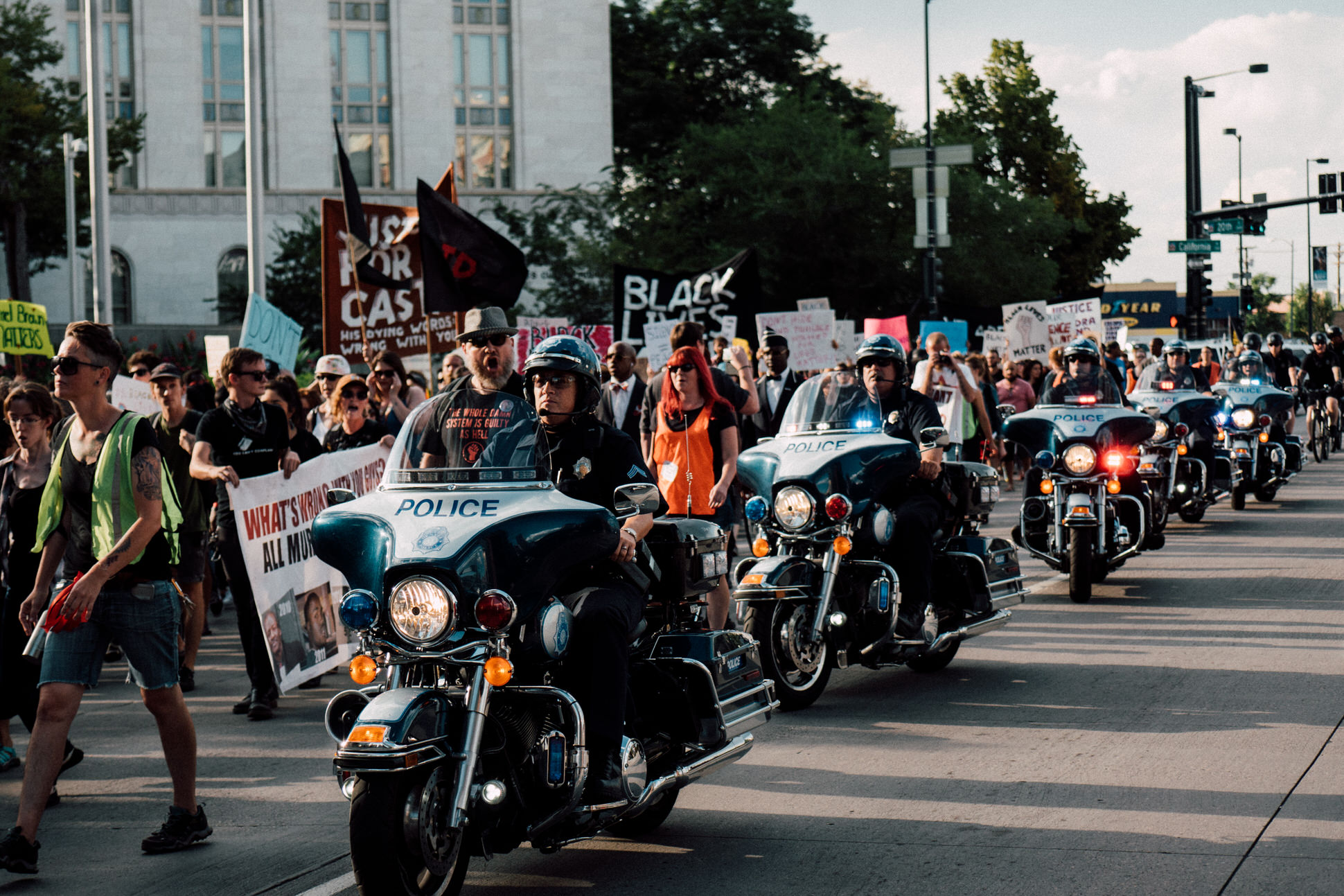 Protesters proceed from Five Points to Civic Center Park via Broadway. Police on bicycles and motorcycles line the road as protesters chant "No justice no peace".