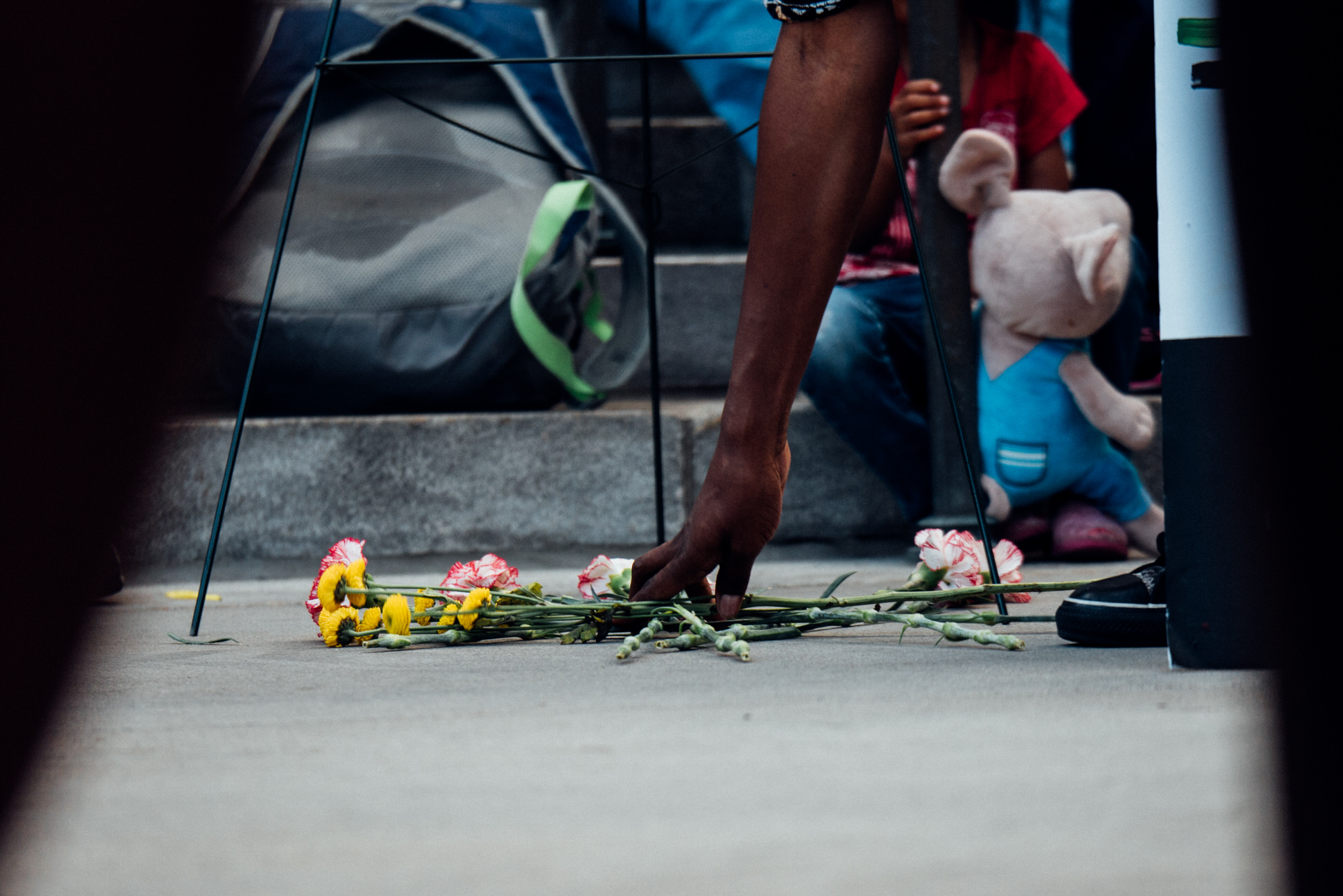 A hand places flowers under a wreath commemorating victims of police violence during the BLM 5280 march in Denver. 