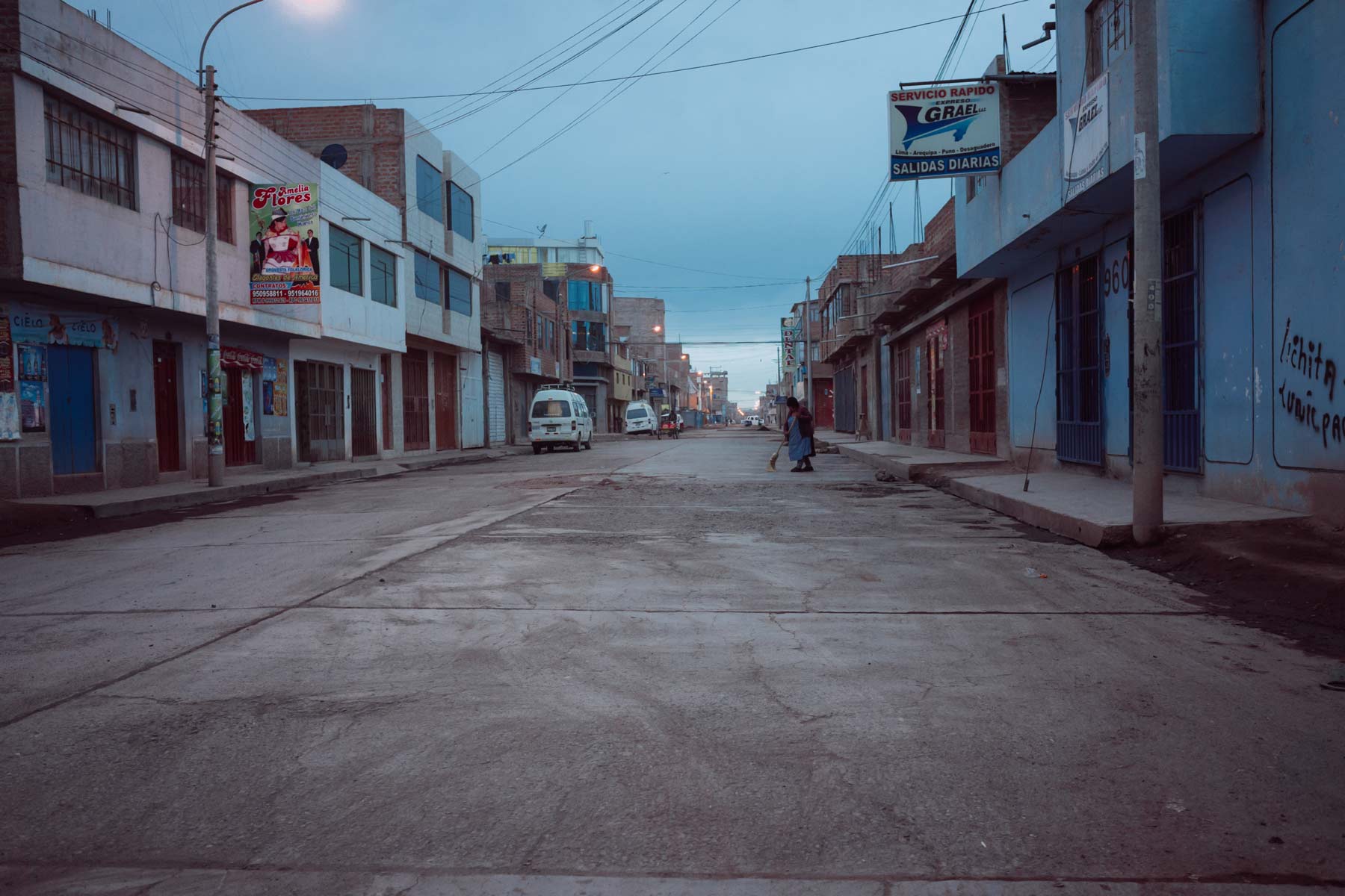 A woman sweeps an empty street as dawn breaks in Juliaca.