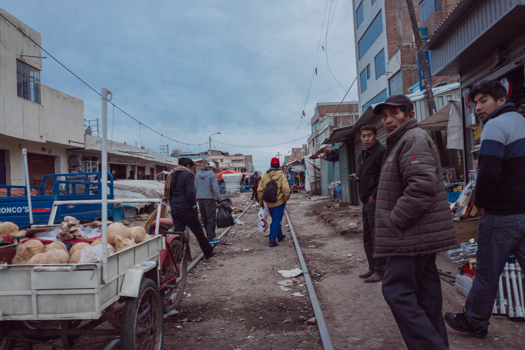 Men walk to work through an outdoor market along Peru's railroad in Juliaca.