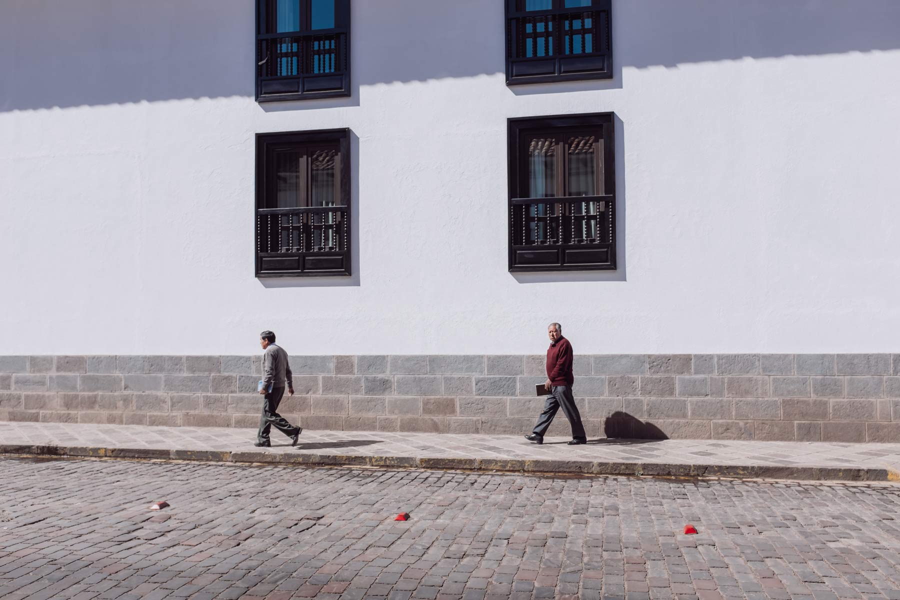 Two men pass in front of a luxury hotel in Cusco.