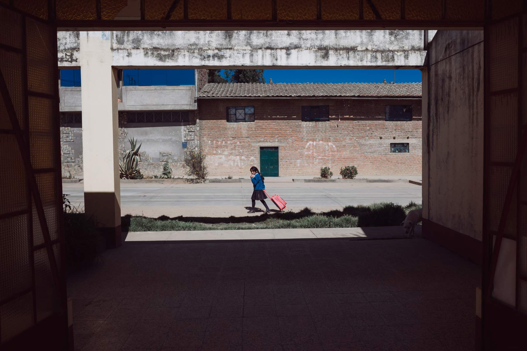 A school girl walking home crosses a large entryway in Hualhuas.